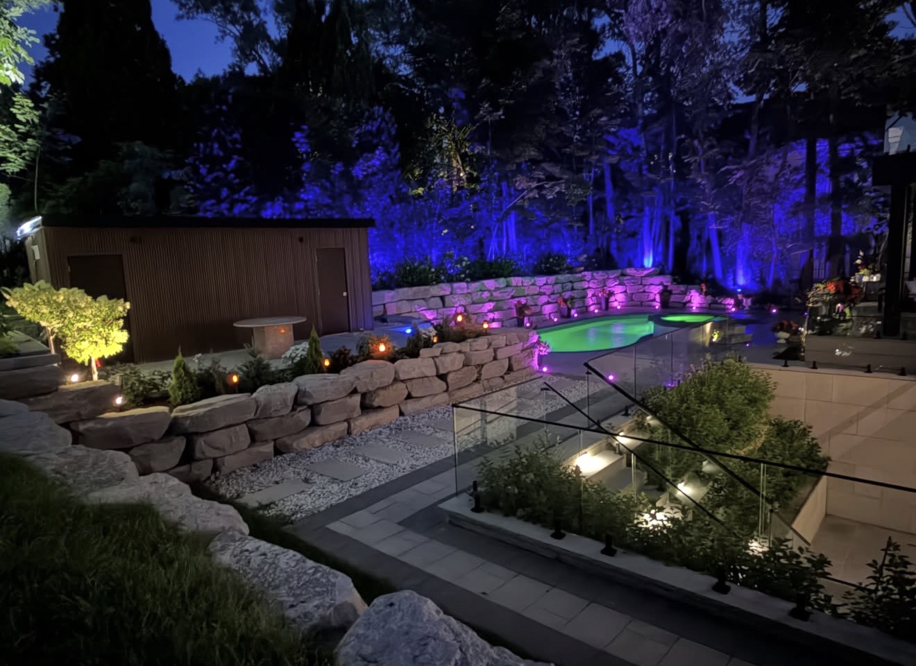 Backyard with colorful landscape uplighting around a pool