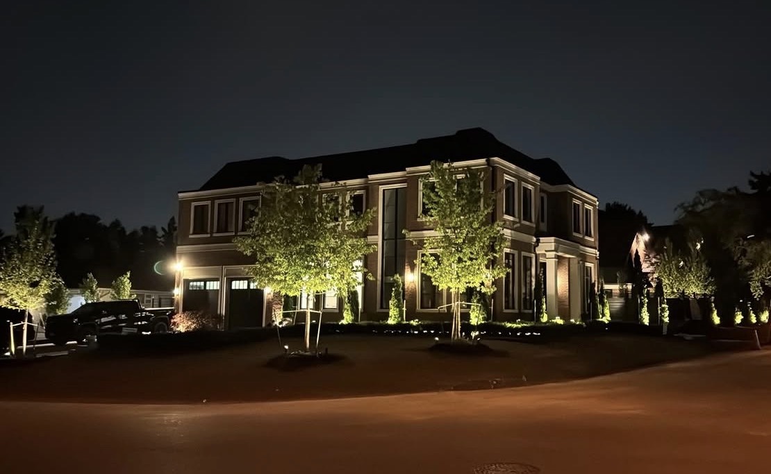 Luxury home exterior with tree uplighting at night
