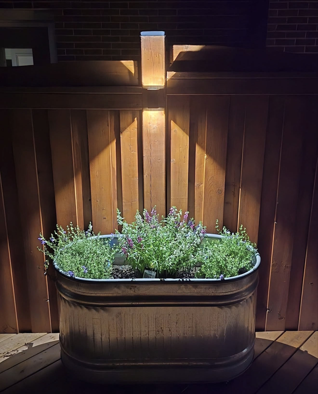 Cedar fence post cap light over a planter of flowers